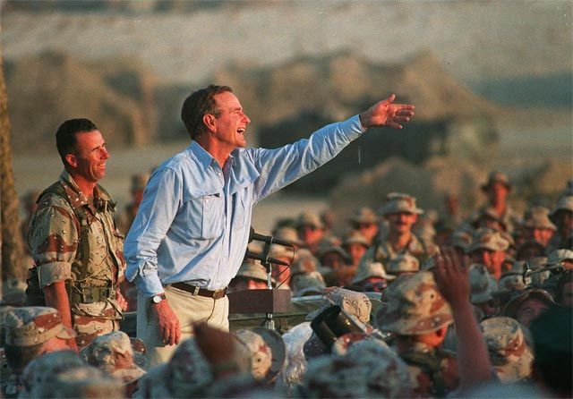 EASTERN SAUDI ARABIA/November 1990--President George Bush tosses presidential tie clips to U.S. Marines at a desert encampment on a Thanksgiving Day visit.